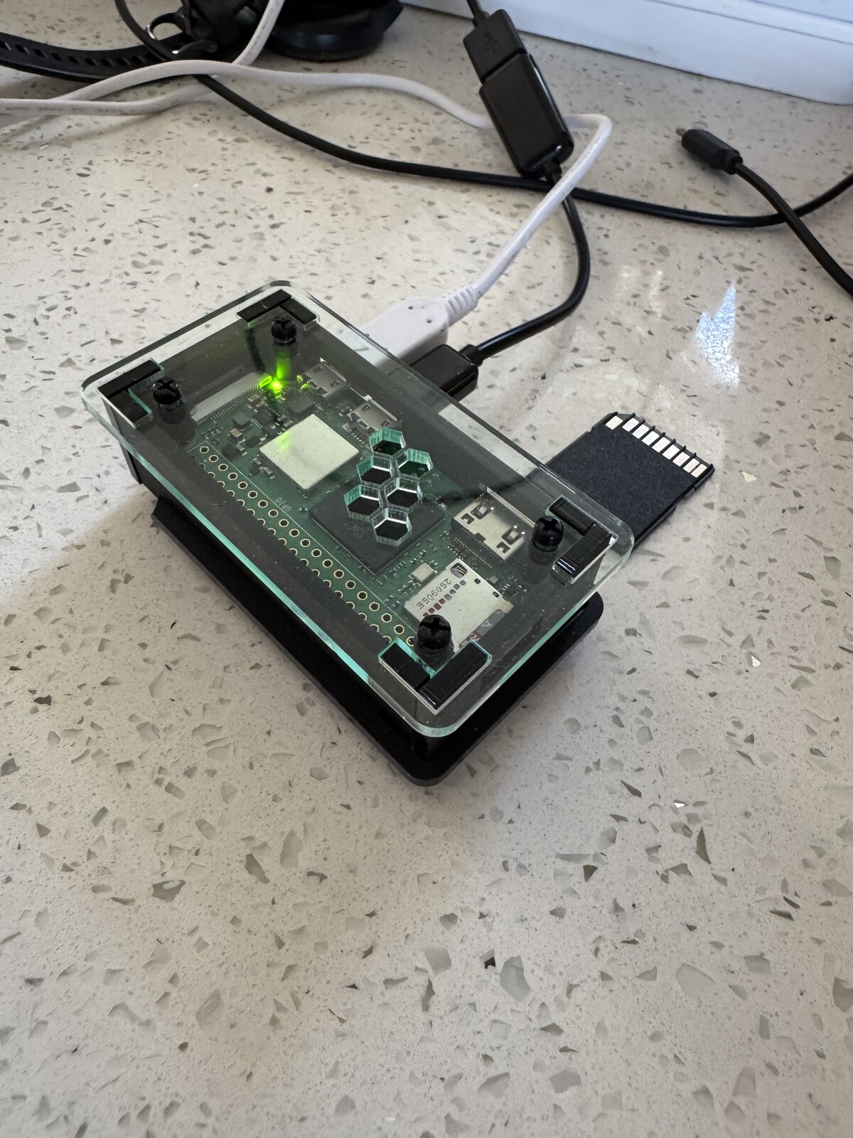 LogFalcon device in a compact enclosure, shown beside an SD card for scale